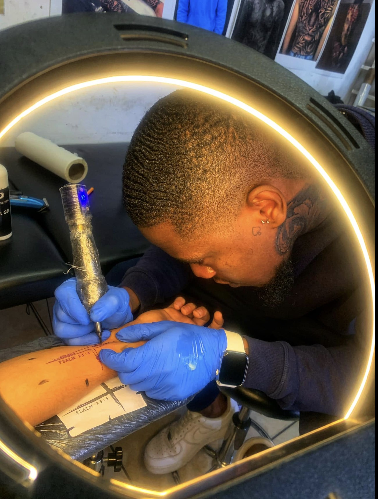Tattoo artist working under a ring light at Professional Black Ink, Rustenburg