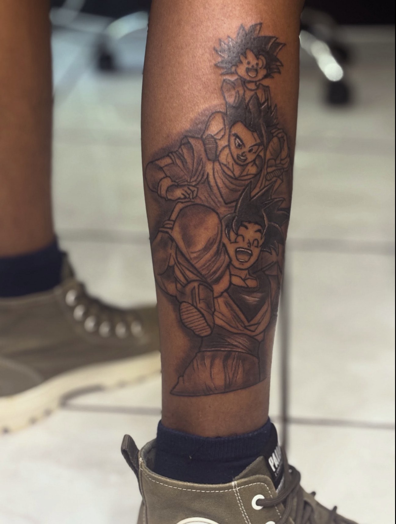 Black-and-grey Dragon Ball Goku sleeve tattoo on the calf — by Professional Black Ink