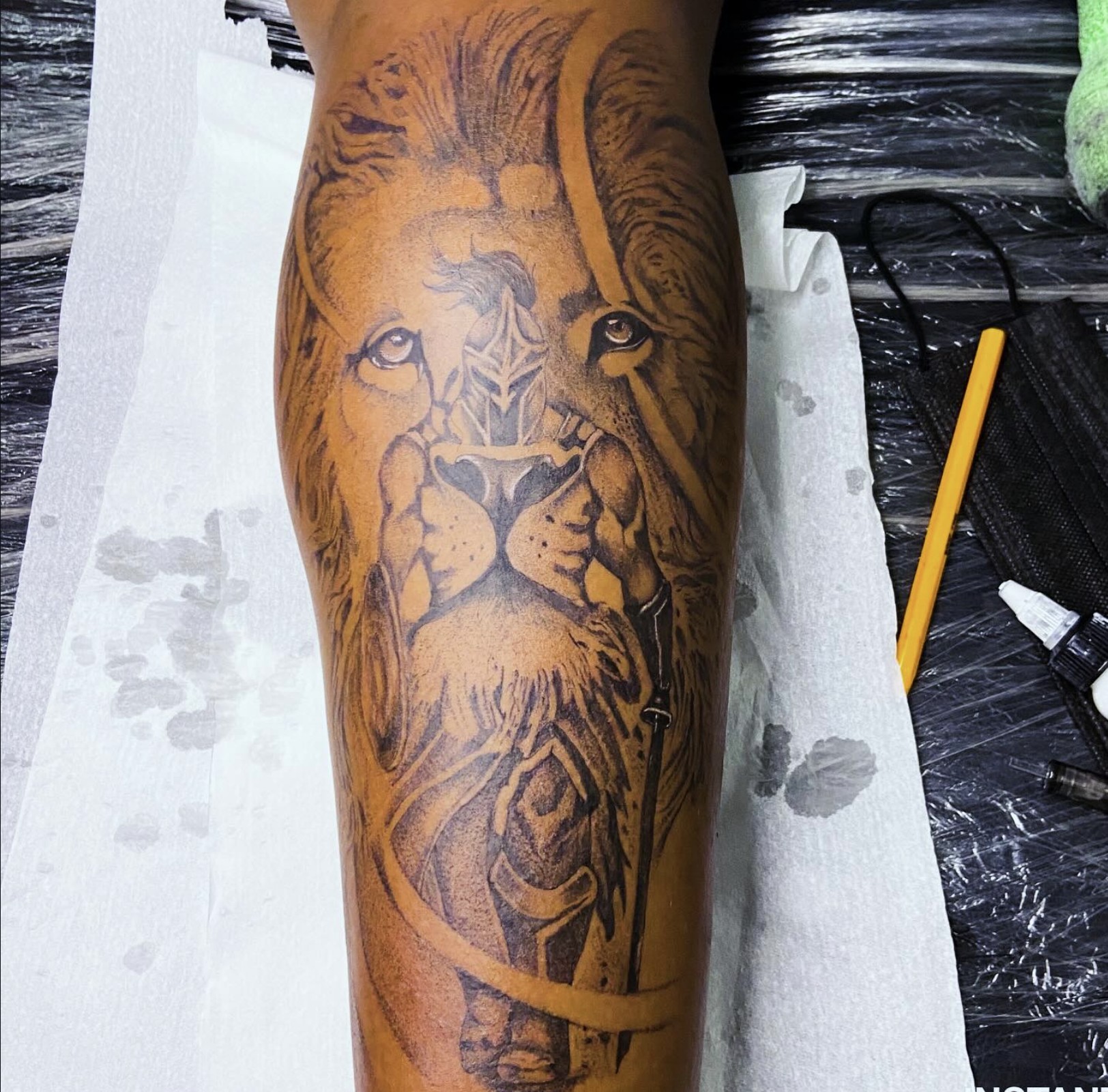 Realism lion and warrior with sword calf tattoo in black and grey — by Professional Black Ink